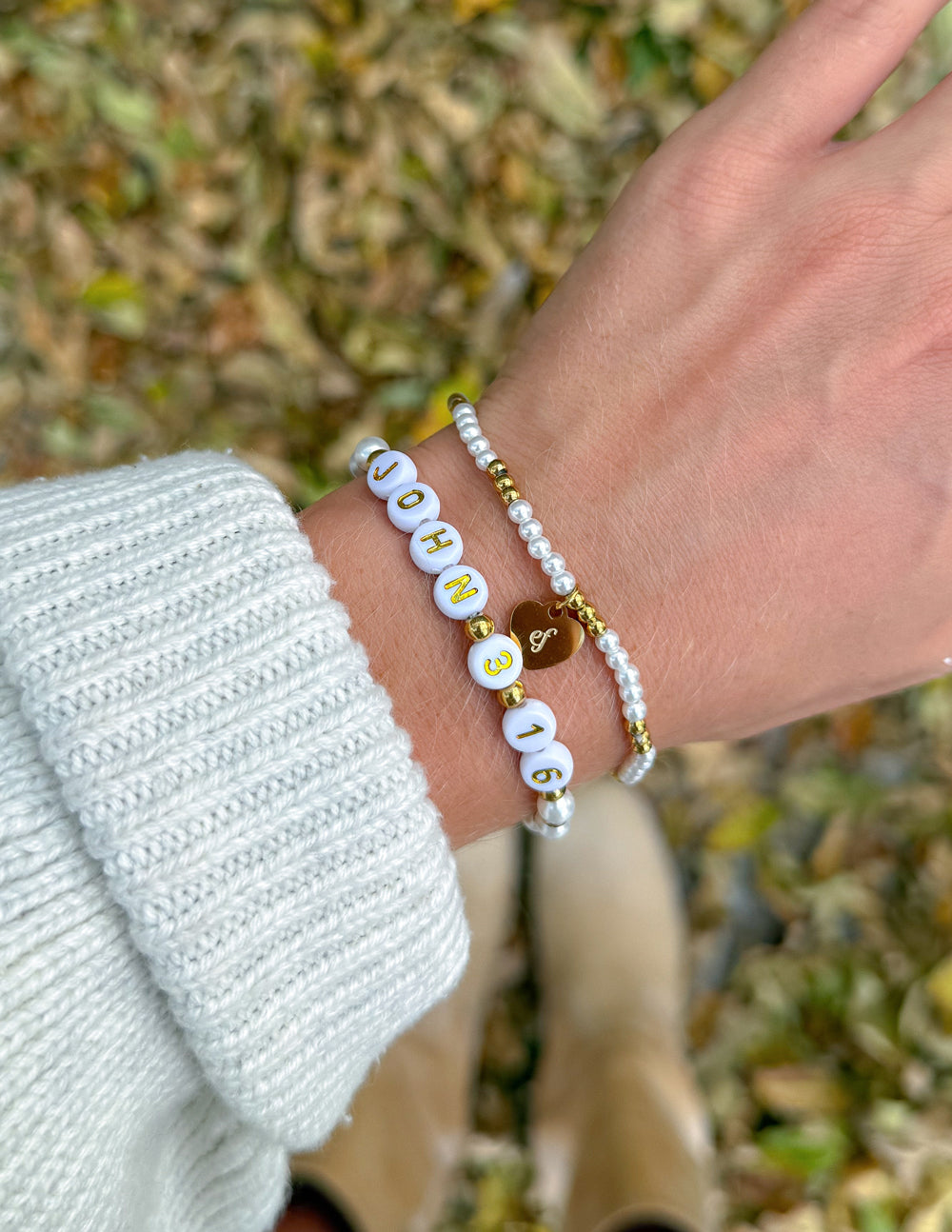 Beaded bracelets on wrist with white and gold beads, 'JOHN 3:16' beads and heart charm
