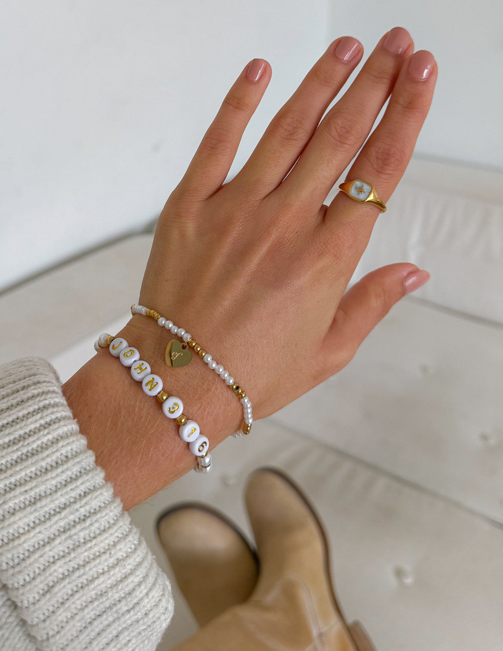 Pair of beaded bracelets on hand with white and gold beads, 'JOHN 3:16' and heart charm