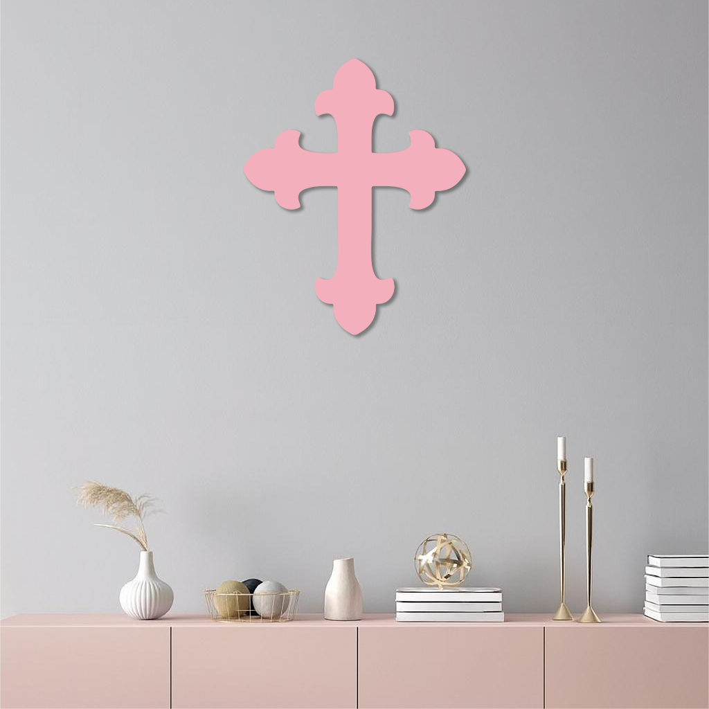 Pink metal cross wall art on a white wall.
