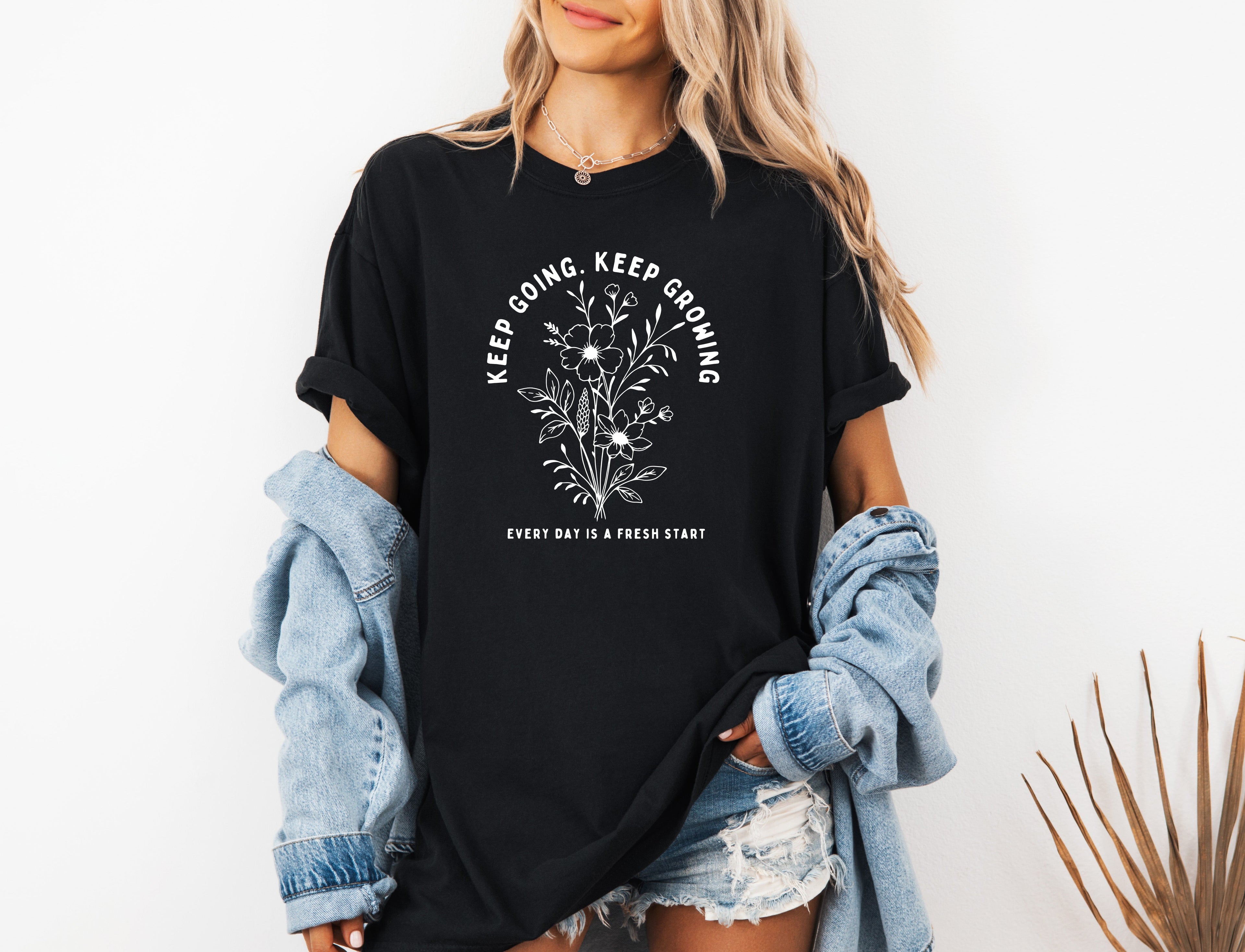 Black unisex T-shirt with white botanical floral quote graphic on front.