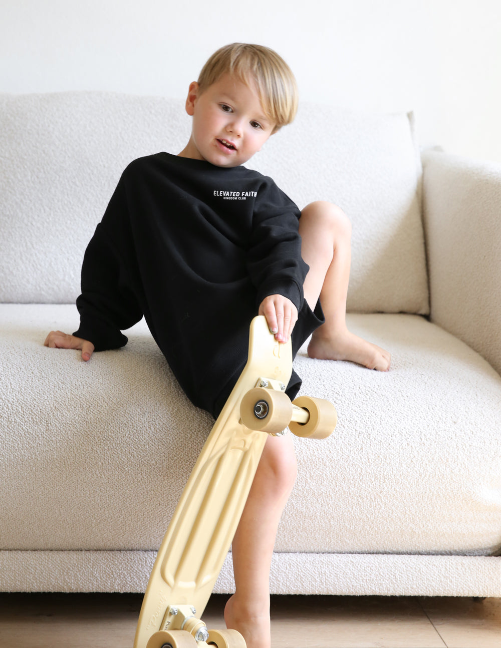 Kids black crewneck sweatshirt with chest graphic, worn with shorts