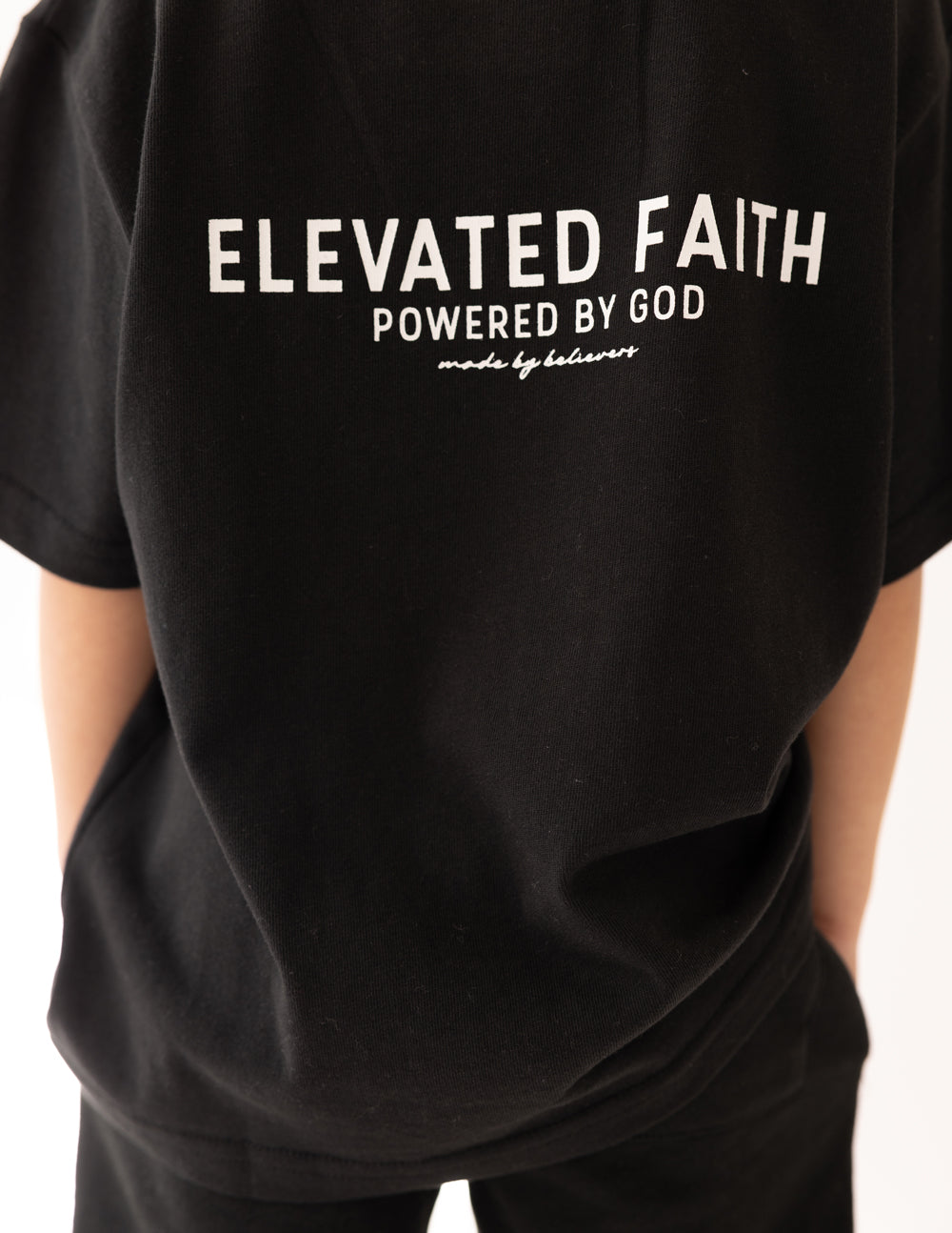 Kids black t-shirt close-up of “Elevated Faith” back text