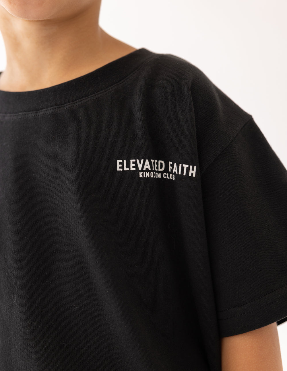 Kids black t-shirt chest logo print reading “Elevated Faith”
