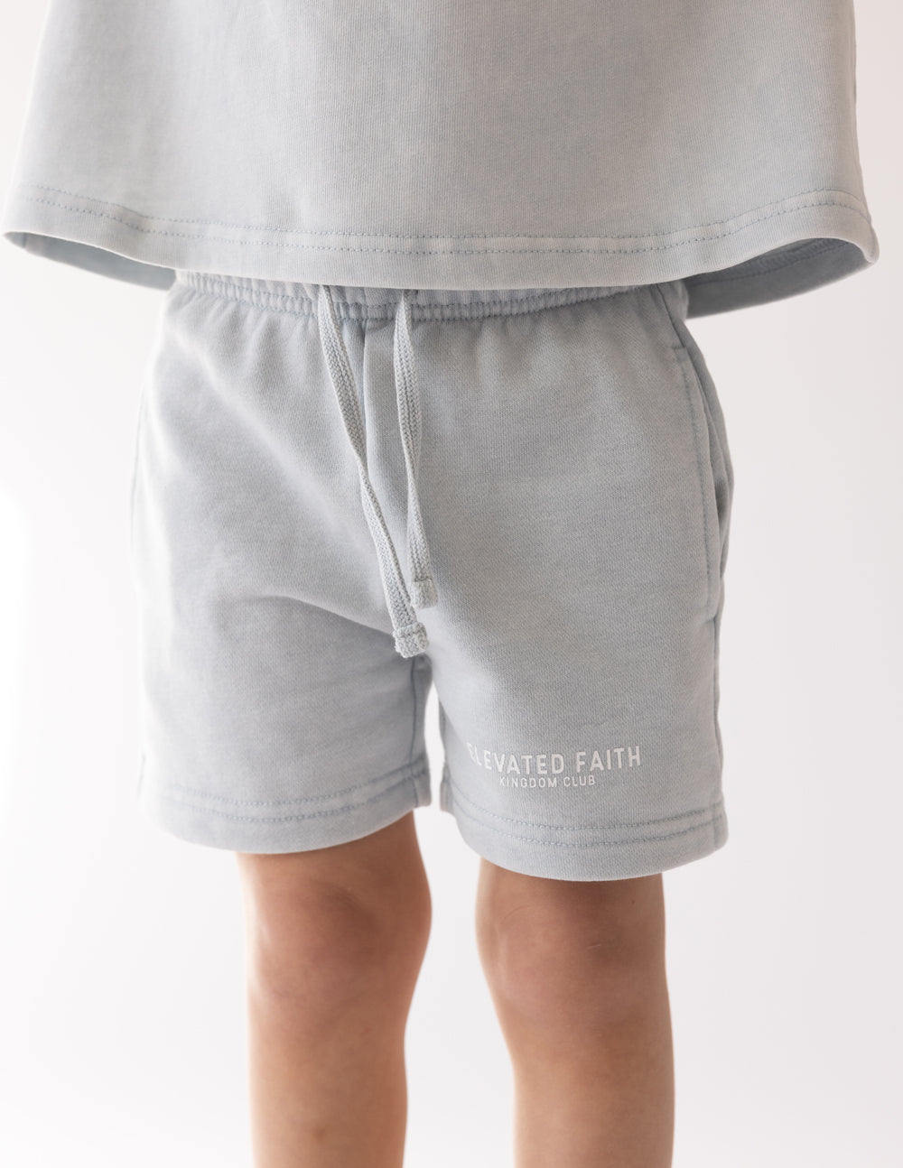 Kids light blue shorts with elastic waistband and front drawstring cord, logo print