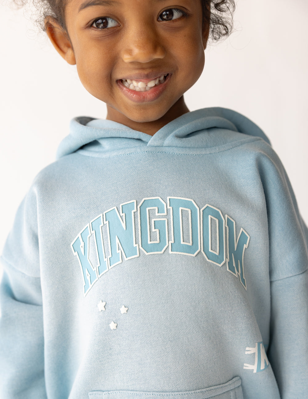 Kids light blue hoodie close-up of Kingdom logo print on chest and hood