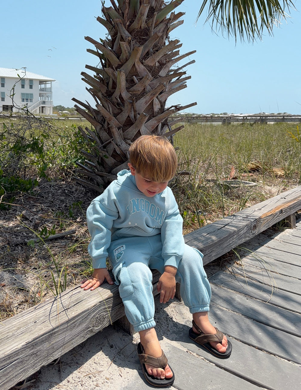 Kids light blue hoodie worn outdoors, Kingdom logo on chest