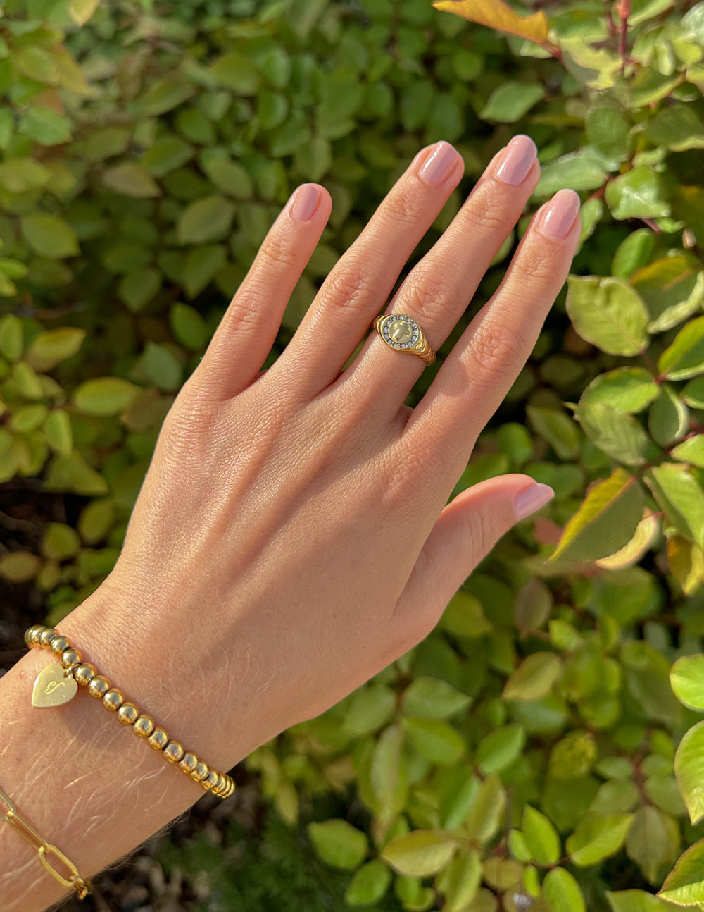 Gold signet ring with cross motif in a round frame with clear stones