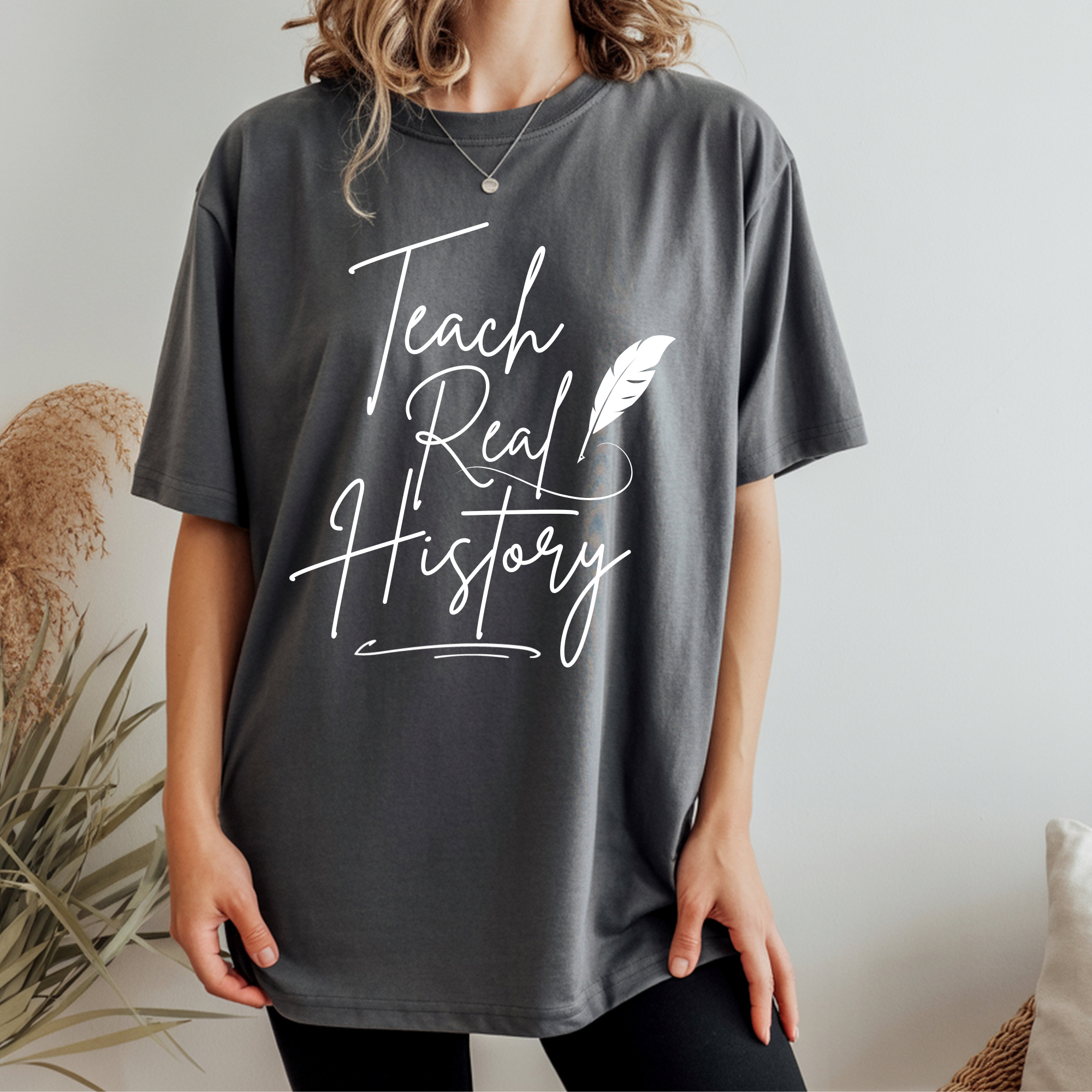 Graphic T-shirt in dark gray with 'Teach Real History' lettering and feather print