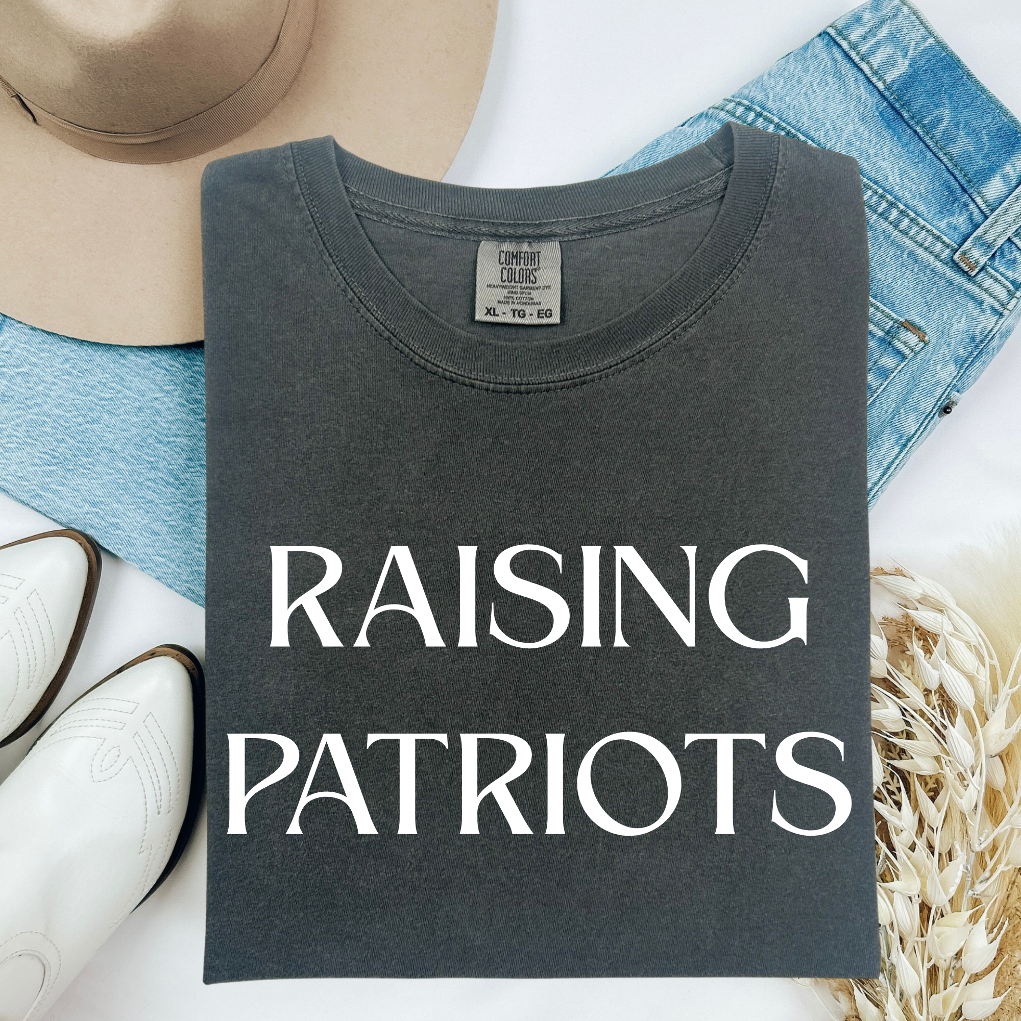 Charcoal Raising Patriots crewneck T-shirt with white text graphic, shown flat on denim