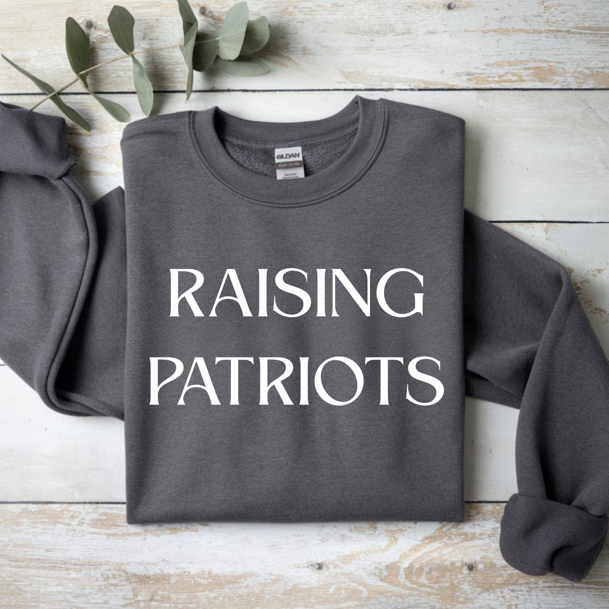 Dark gray crewneck sweatshirt with white 'RAISING PATRIOTS' front print.