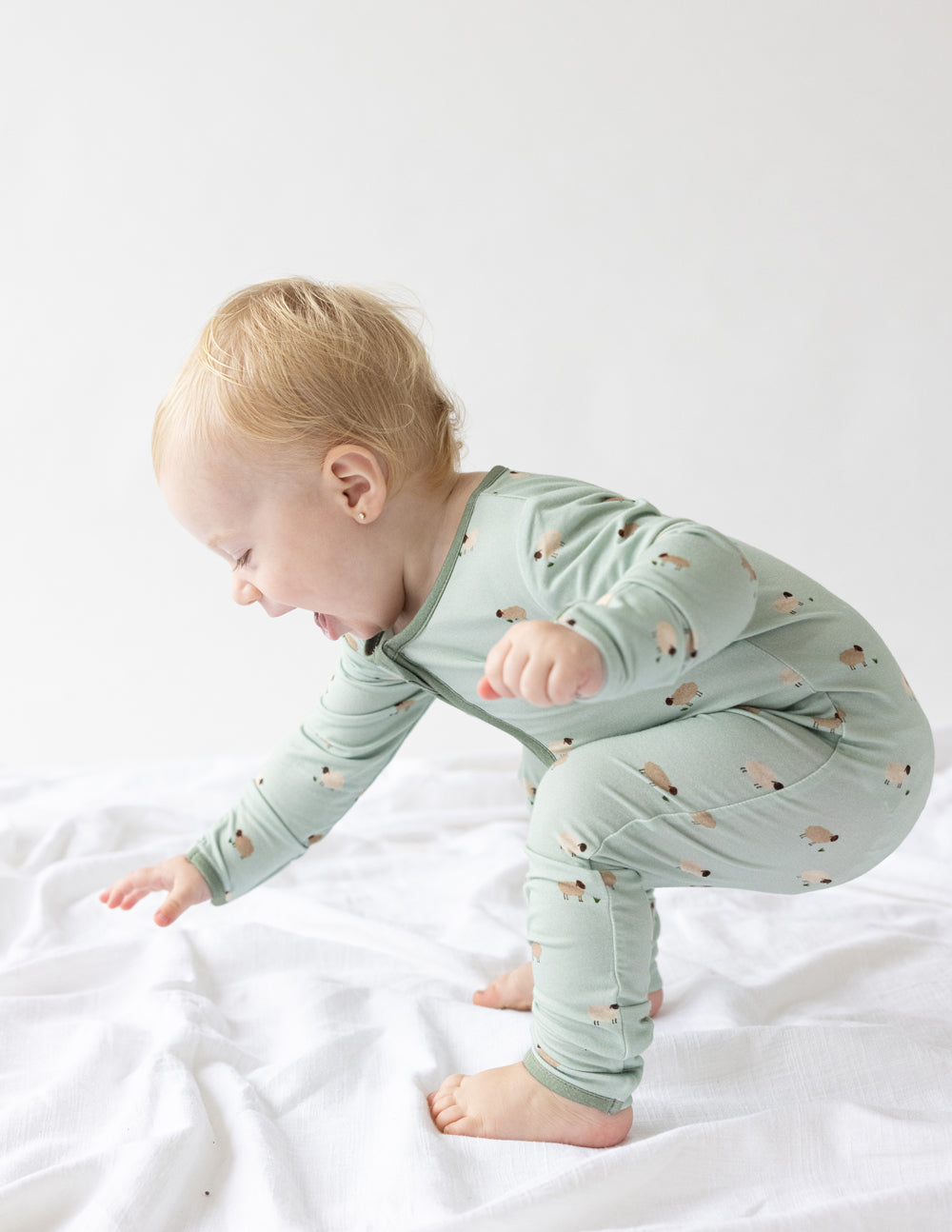 Sage green lamb-print baby onesie with long sleeves and front zip