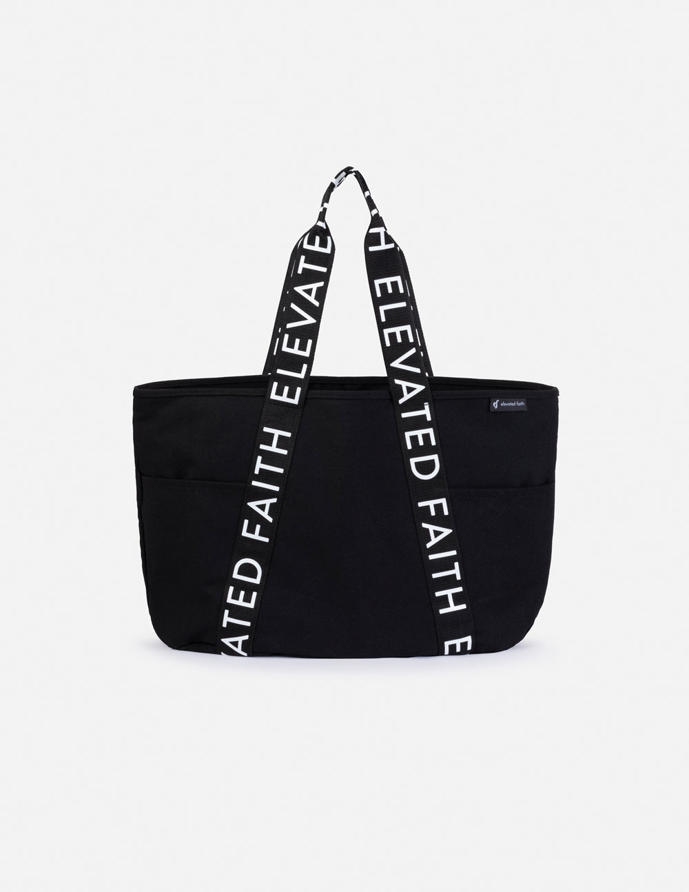 Black large tote bag with two top handles and “ELEVATED FAITH” text along the straps