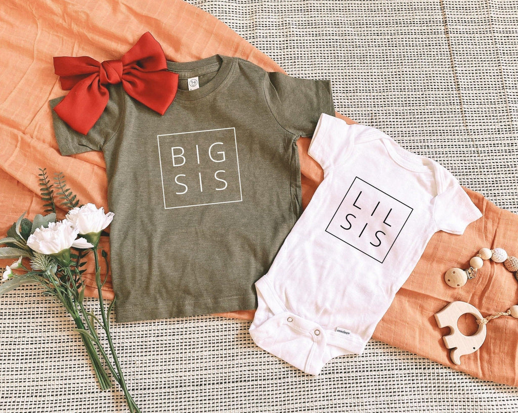 Two baby bodysuits: gray with BIG SIS and white with LIL SIS, bow accents