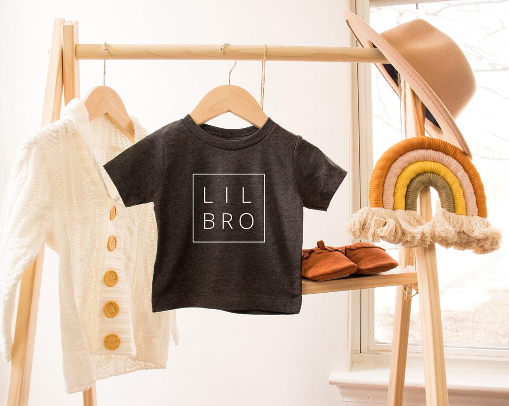 Black baby toddler T-shirt with Lil Bro square text graphic on hanger