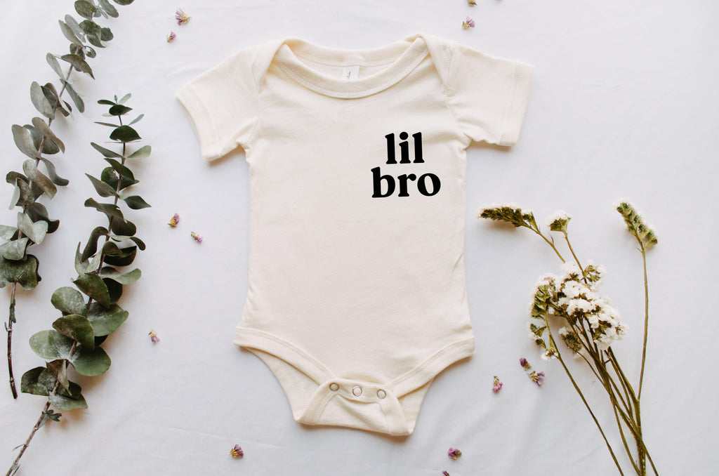 White baby onesie bodysuit with short sleeves and black "lil bro" text at chest