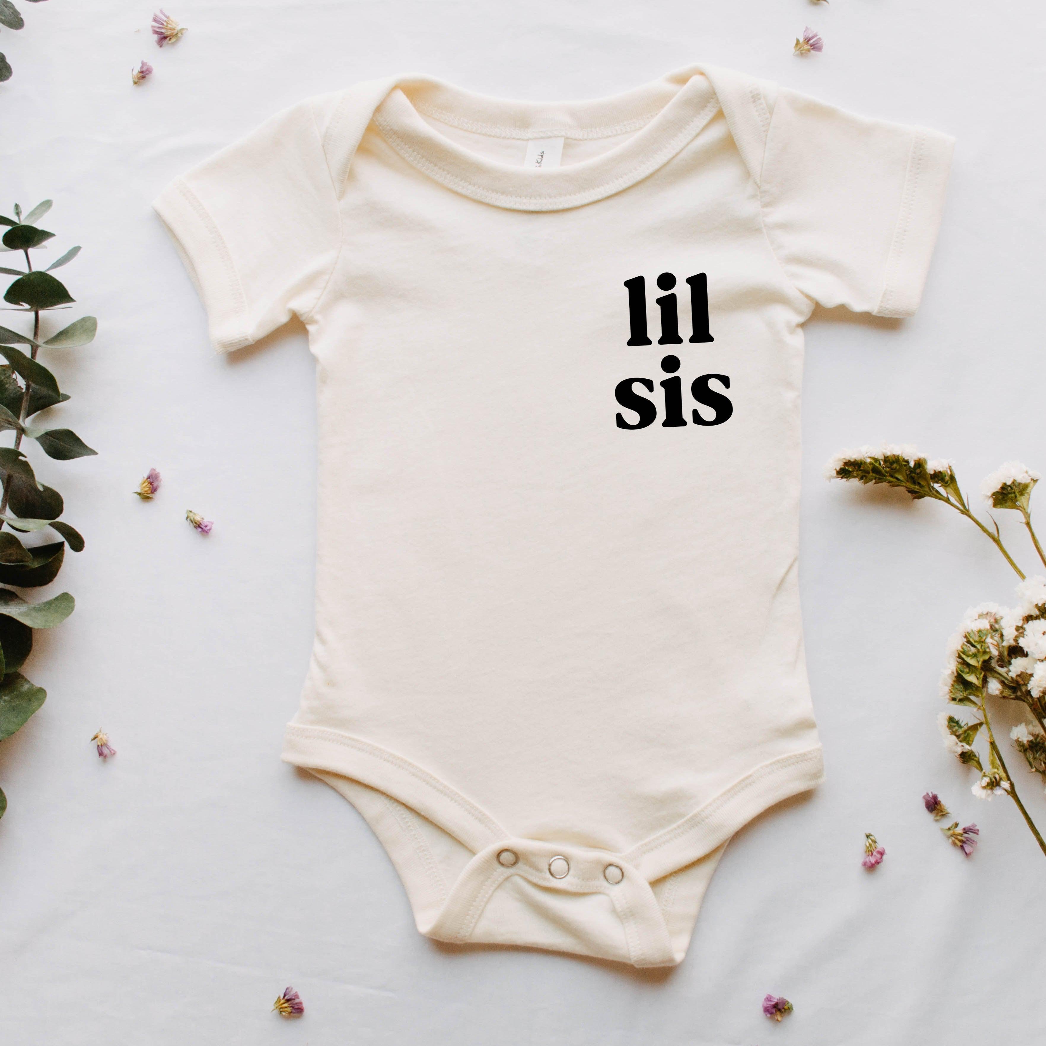 Cream baby onesie with 'lil sis' chest print, short sleeves and snap legs