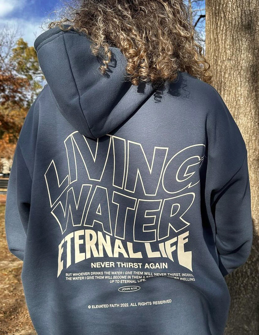Dark blue hoodie back with Living Water Eternal Life typography graphic close-up.