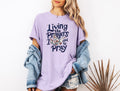 Garment-dyed T-shirt in lavender, crewneck with front bird and 'Pray' graphic.