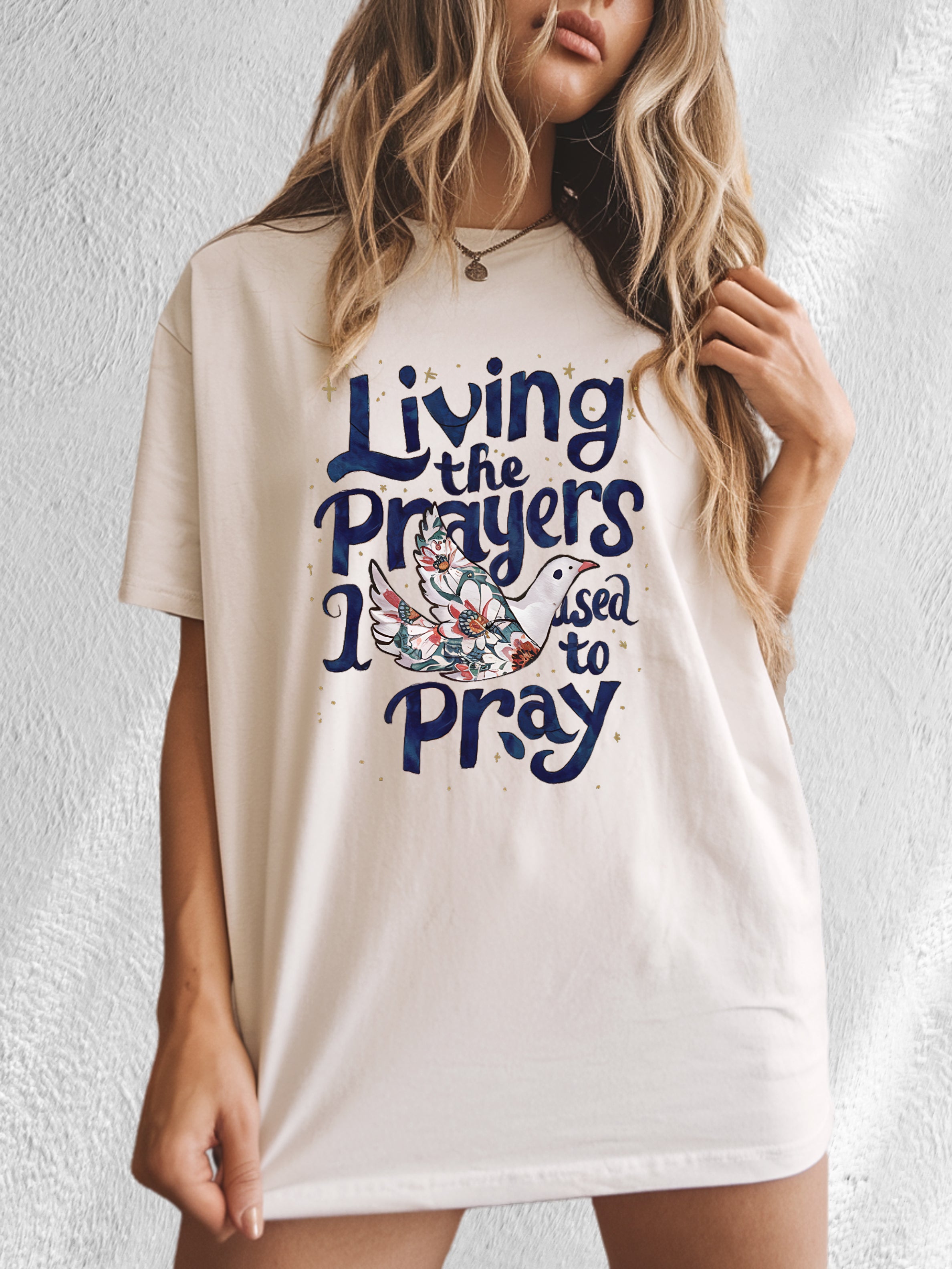 Ivory unisex t-shirt with “Living the Prayers…Pray” front graphic