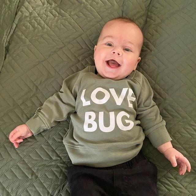 Green baby pullover with white “LOVE BUG” text graphic on front