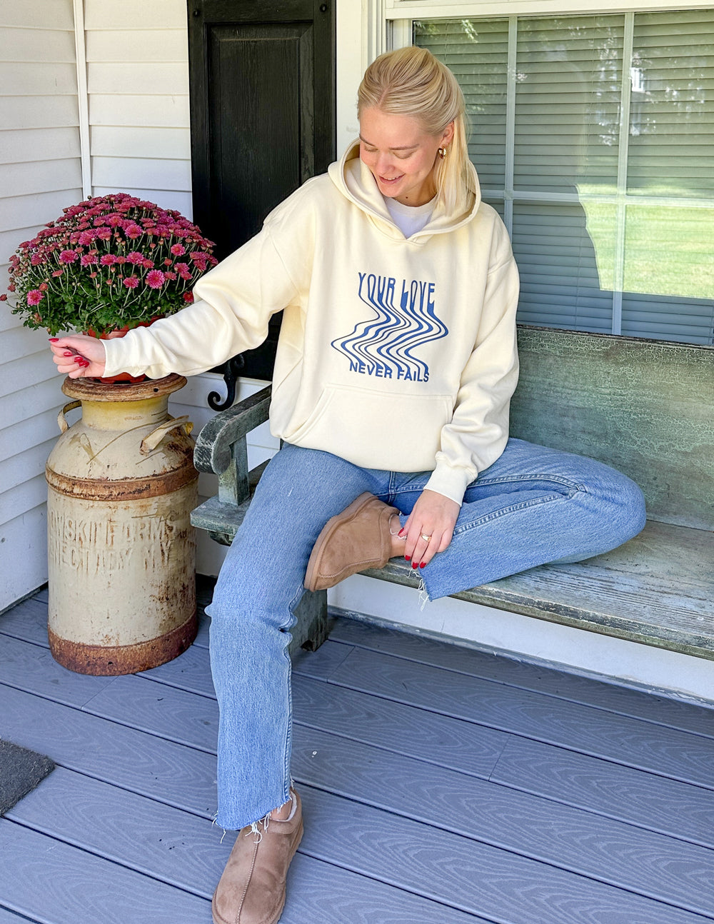 Cream unisex hoodie, blue 'Your Love Never Fails' graphic on chest, front pocket