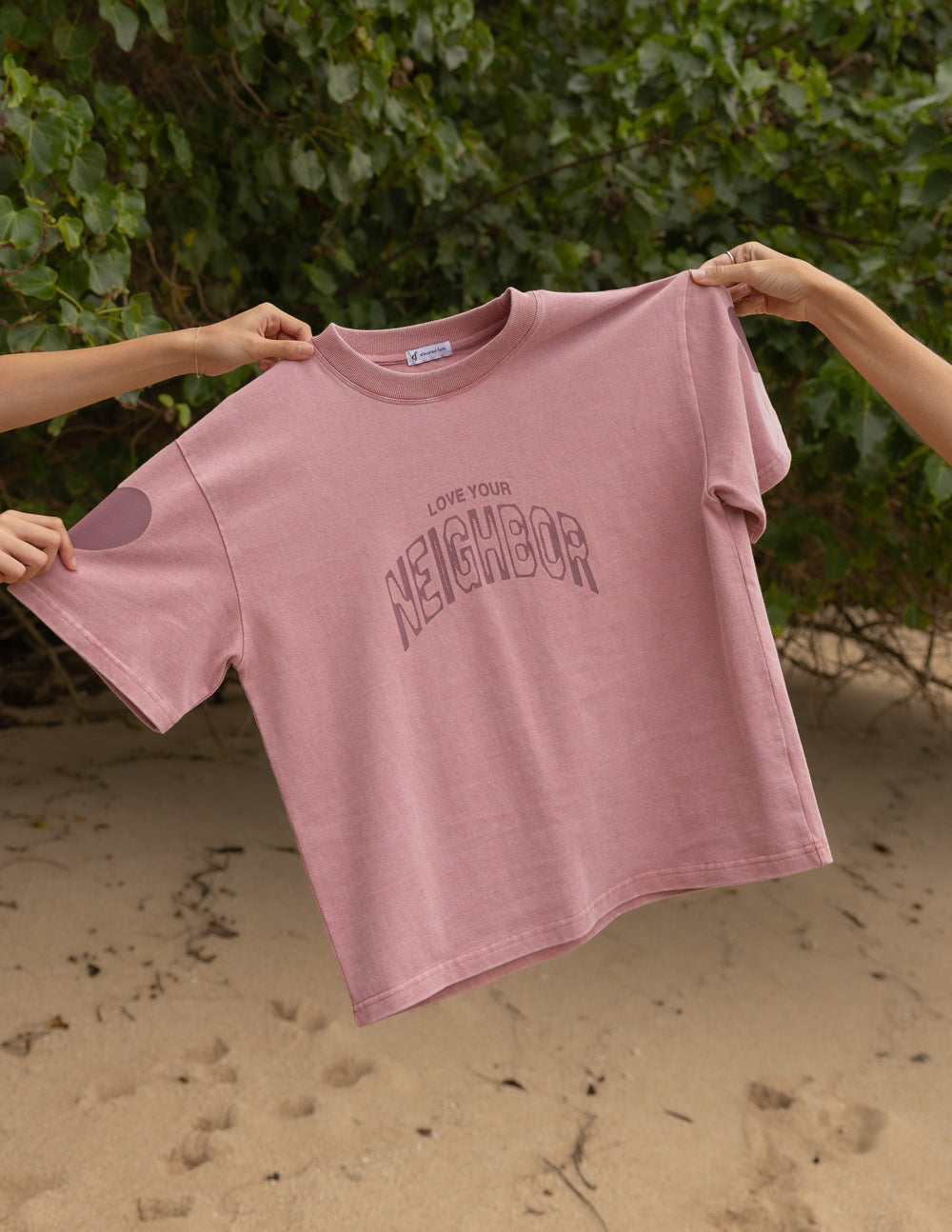 Pink heavyweight T-shirt with crew neck and 'Neighbor' front graphic logo, laid flat