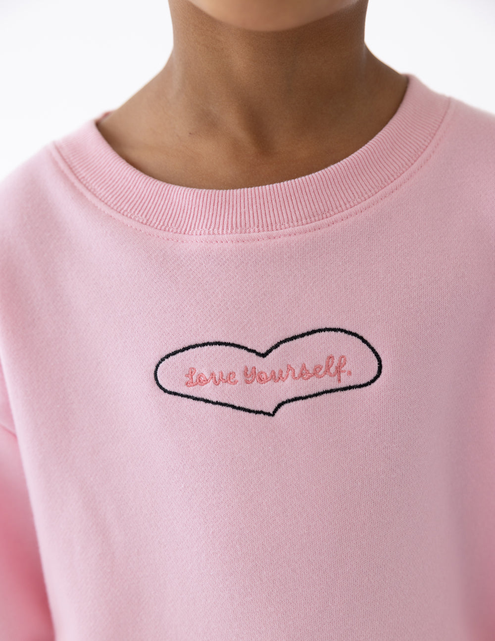 Pink crewneck neckline with embroidered heart outline graphic and “Love yourself” text