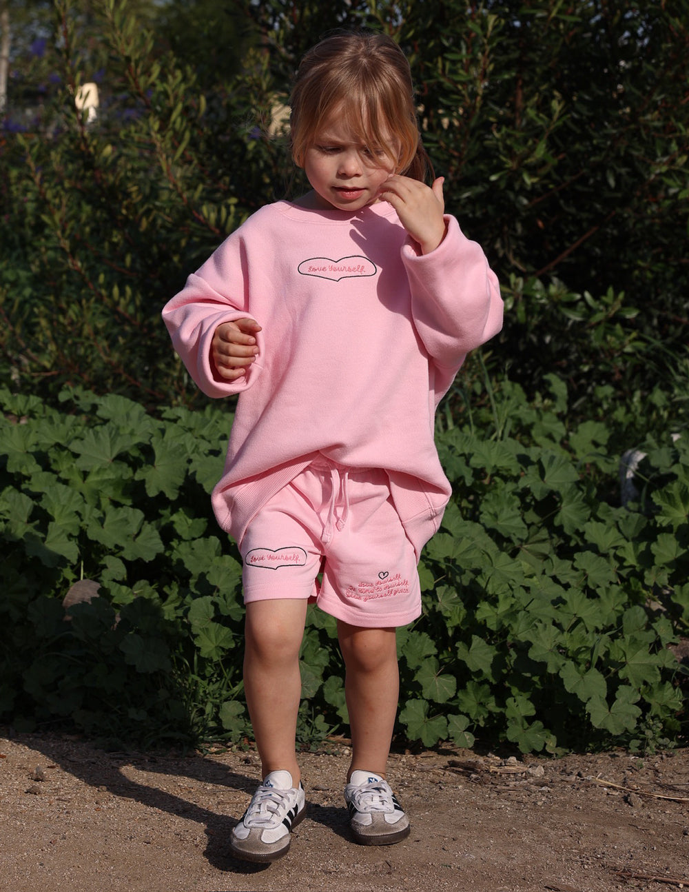Kids pink crewneck sweatshirt with heart outline graphic; long sleeves and ribbed hem