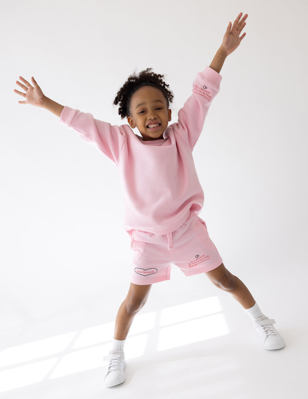 Kids pink shorts with elastic drawstring waist and heart graphic on leg