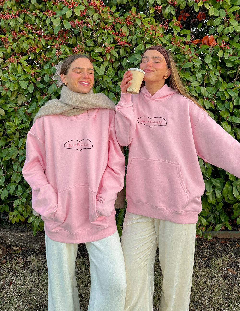 Pink unisex hoodie with heart-shaped “Love Yourself” logo and front kangaroo pocket.