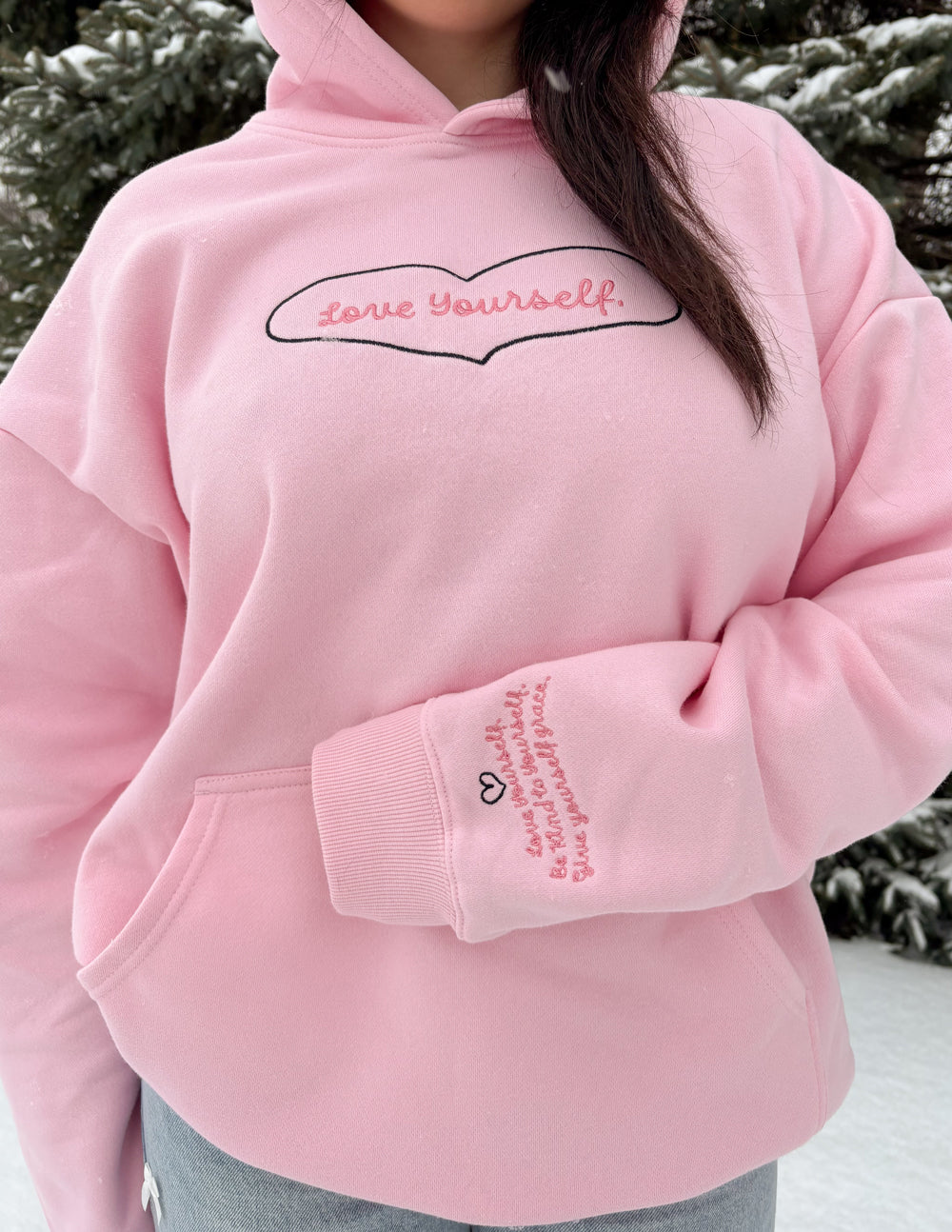 Pink unisex hoodie with hood and heart-shaped “Love Yourself” logo on the chest.