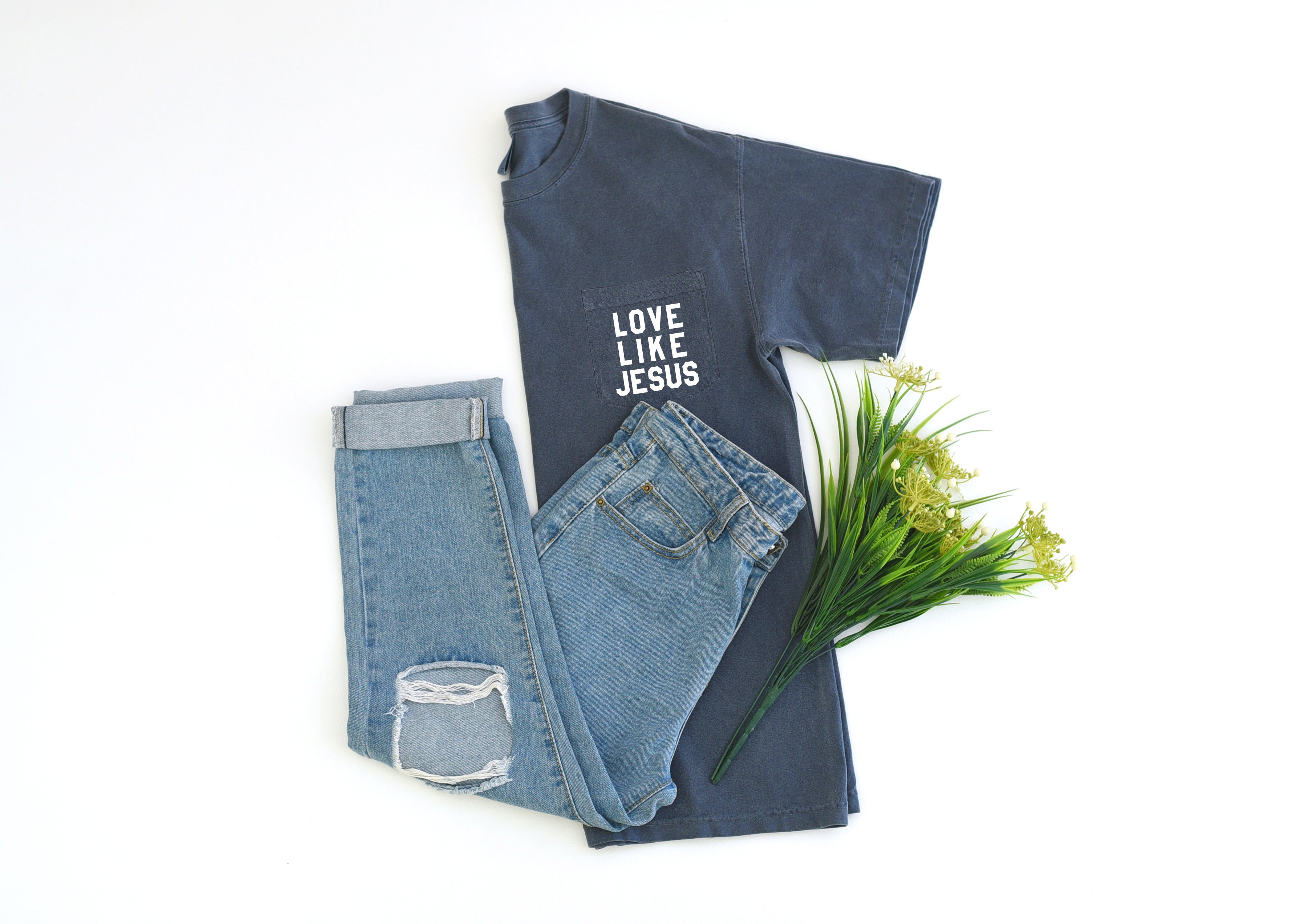 Folded pocket T-shirt stack, dark gray-blue, with “LOVE LIKE JESUS” logo on chest.
