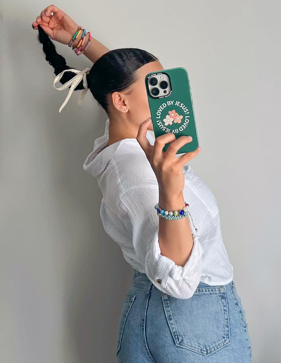 Green phone case with floral print and 'LOVED BY JESUS' text, lens cutouts