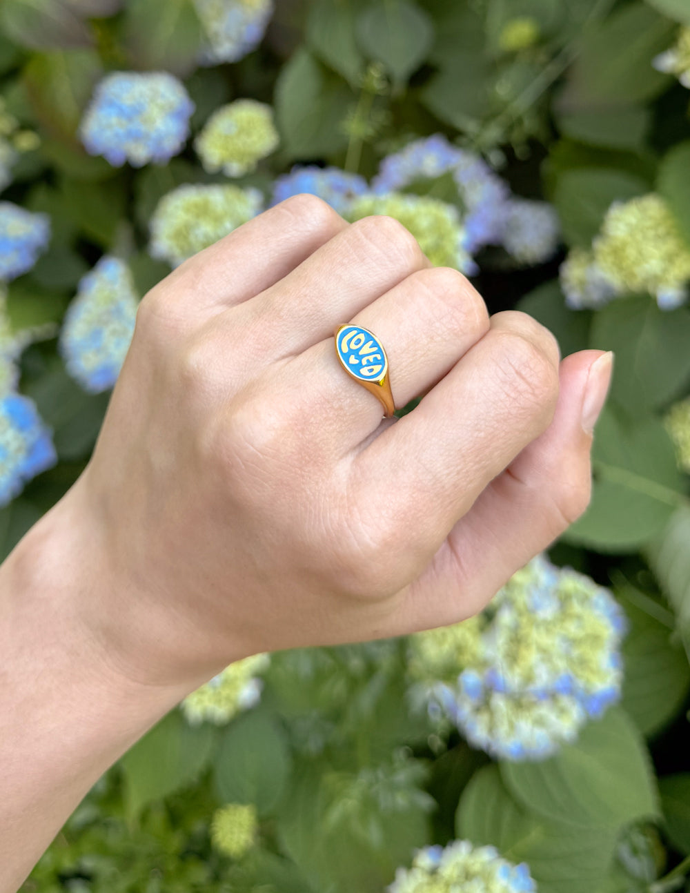 Gold signet ring with blue enamel oval face marked LOVED on hand
