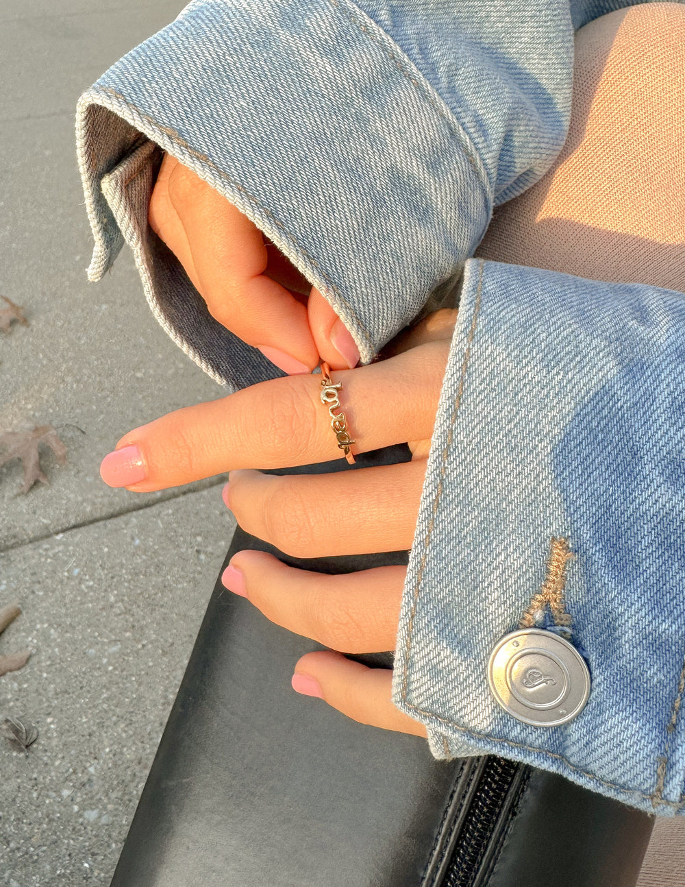 Gold-tone Loved ring on finger, shown in side view