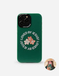 Green phone case back with floral print and 'LOVED BY JESUS' text, camera cutouts
