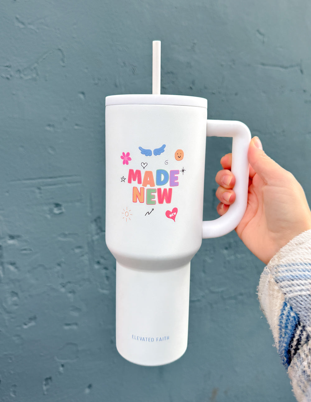 White 40 oz tumbler with handle and straw lid, held in hand; “Made New” graphic
