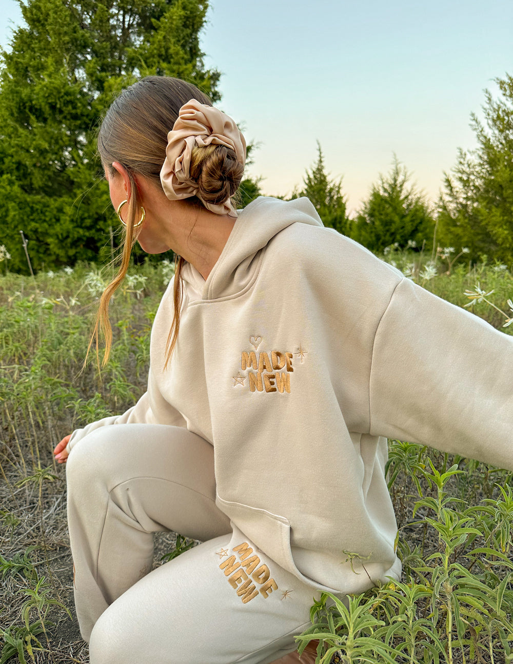 Cream unisex hoodie with hood, front logo print, and printed graphic on cuff