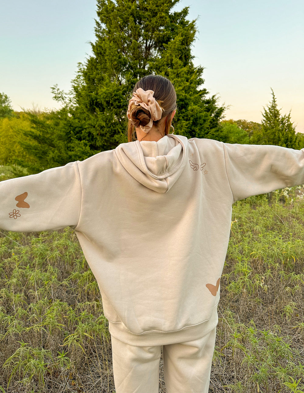 Cream unisex hoodie with hood and large front print, worn with arms out