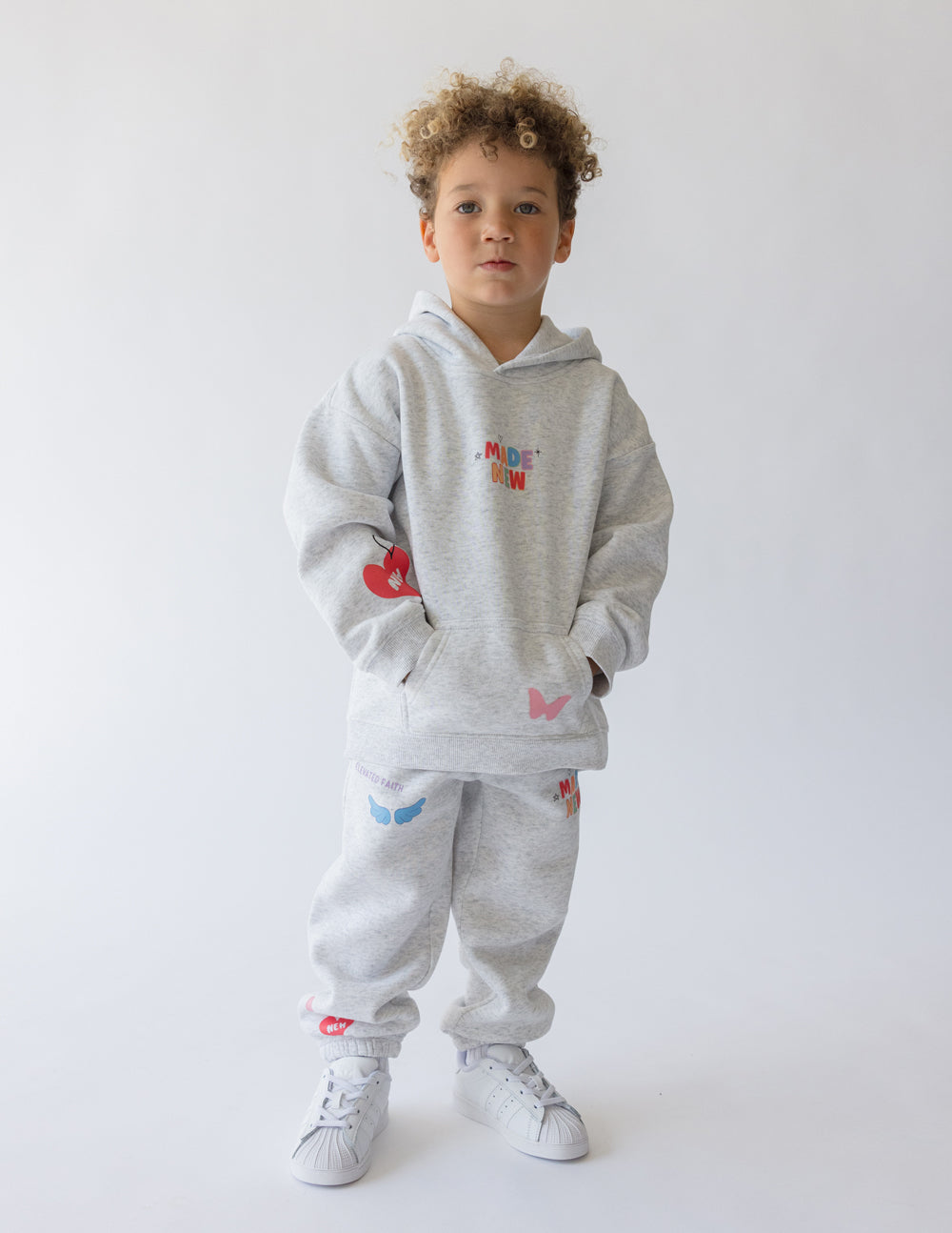 Kids light gray hoodie worn with colorful front graphic and kangaroo pocket