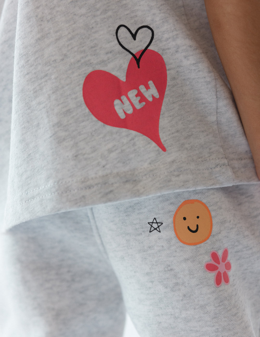 Kids grey tee close-up: red heart 'NEW' and smiley face with star icon
