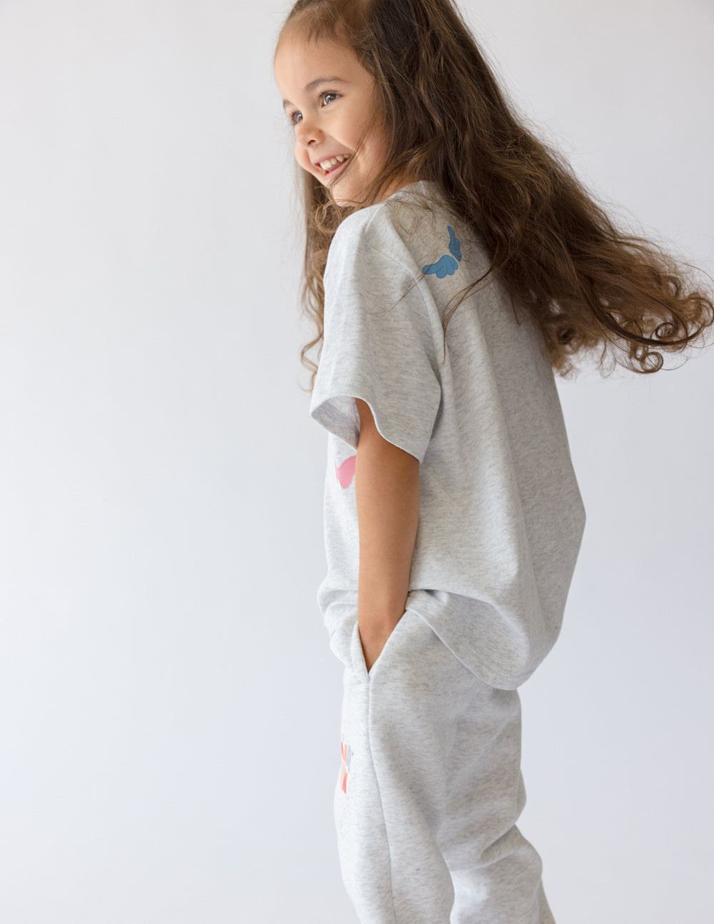 Kids grey tee with small blue dinosaur graphic on the side of the chest