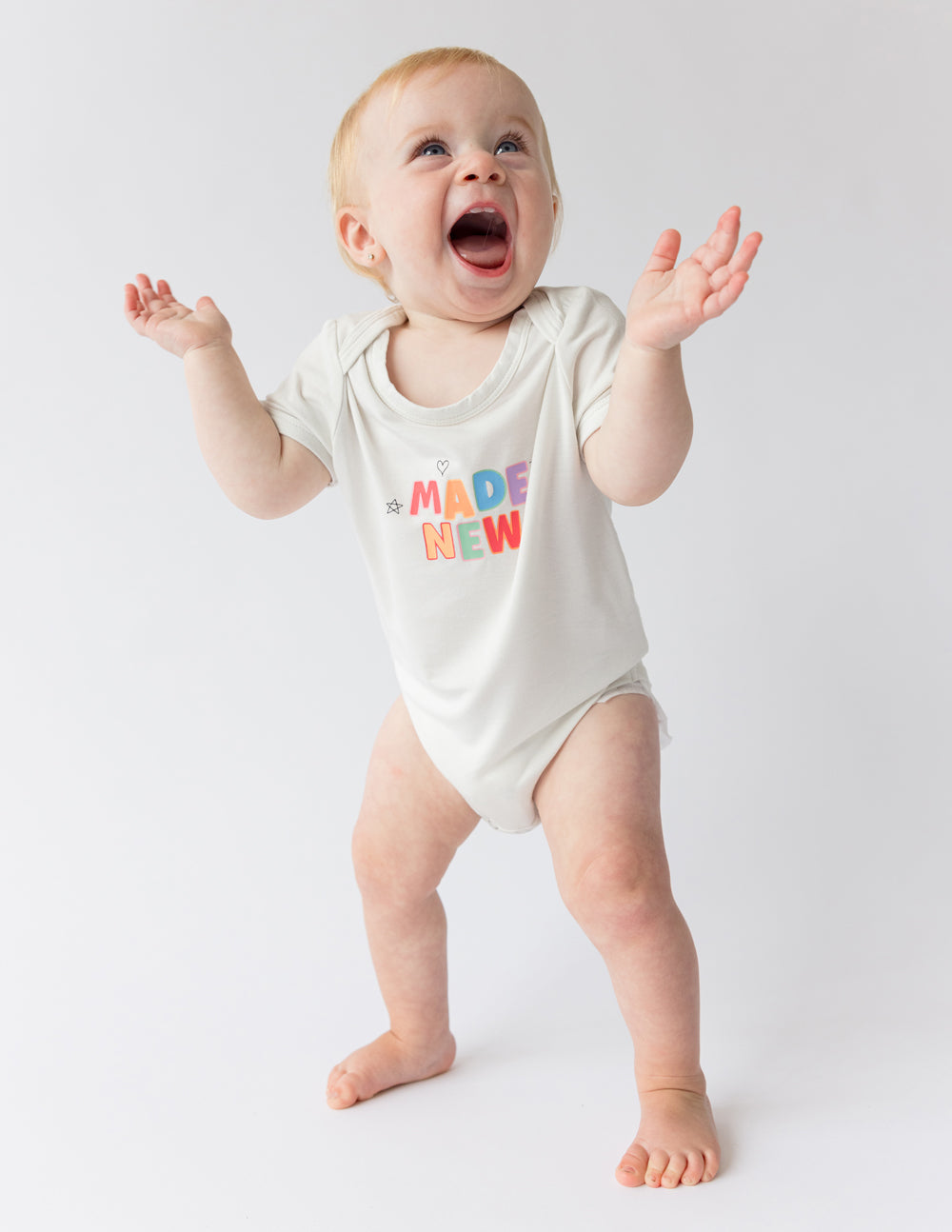 White baby onesie with "MADE NEW" graphic, short sleeves