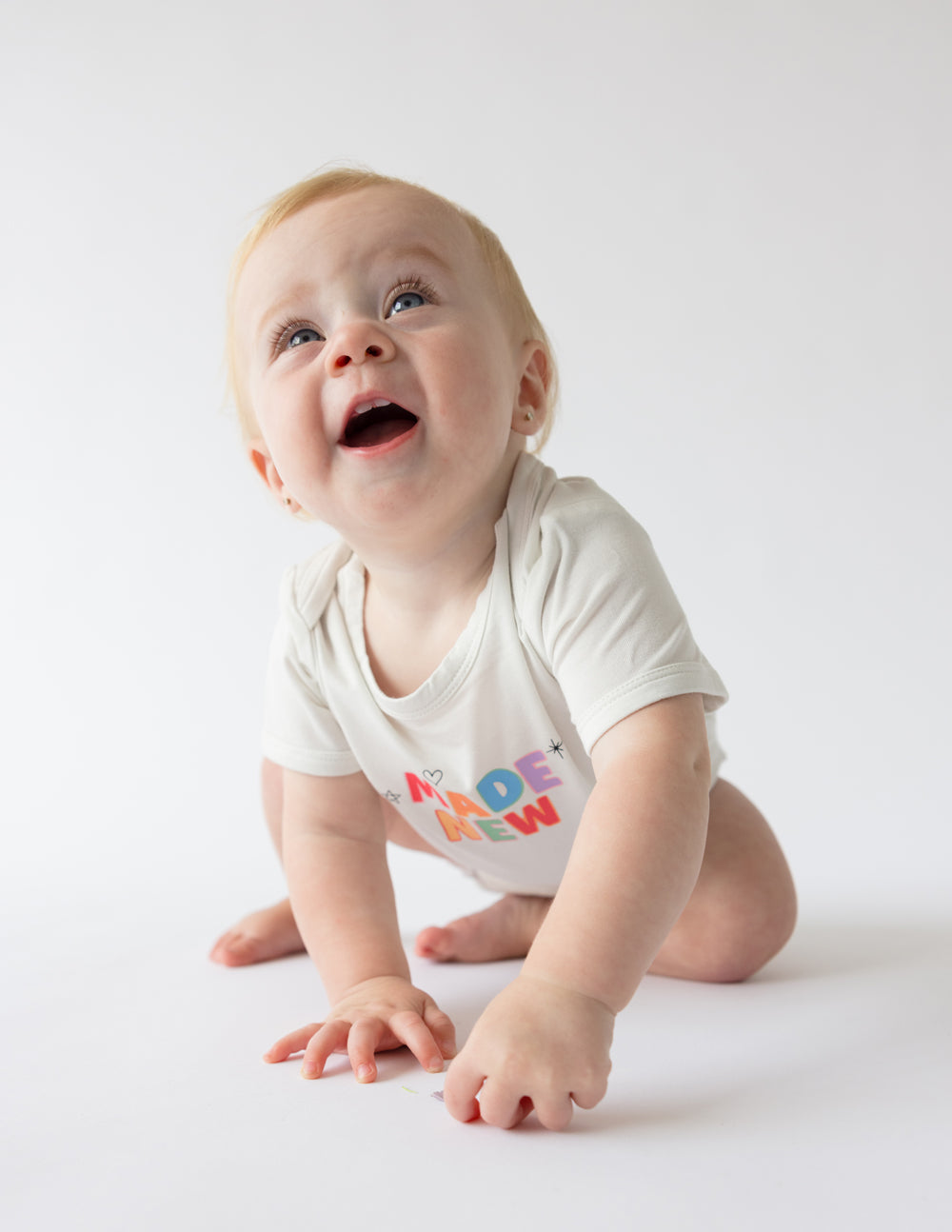 White baby onesie with short sleeves and "MADE NEW" graphic