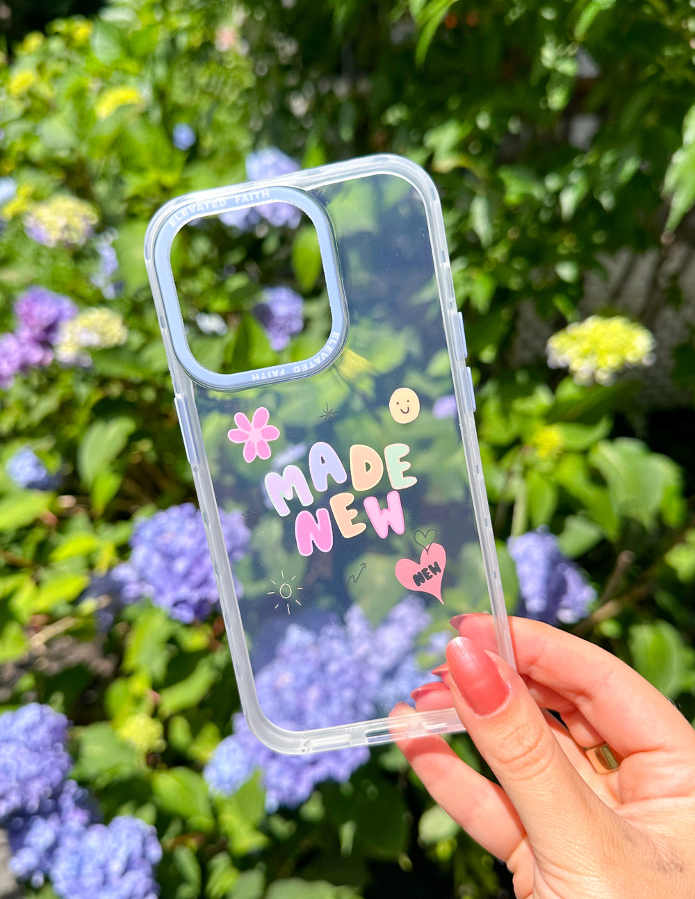 Clear-edged phone case with 'MADE NEW' graphic and icons, held in hand