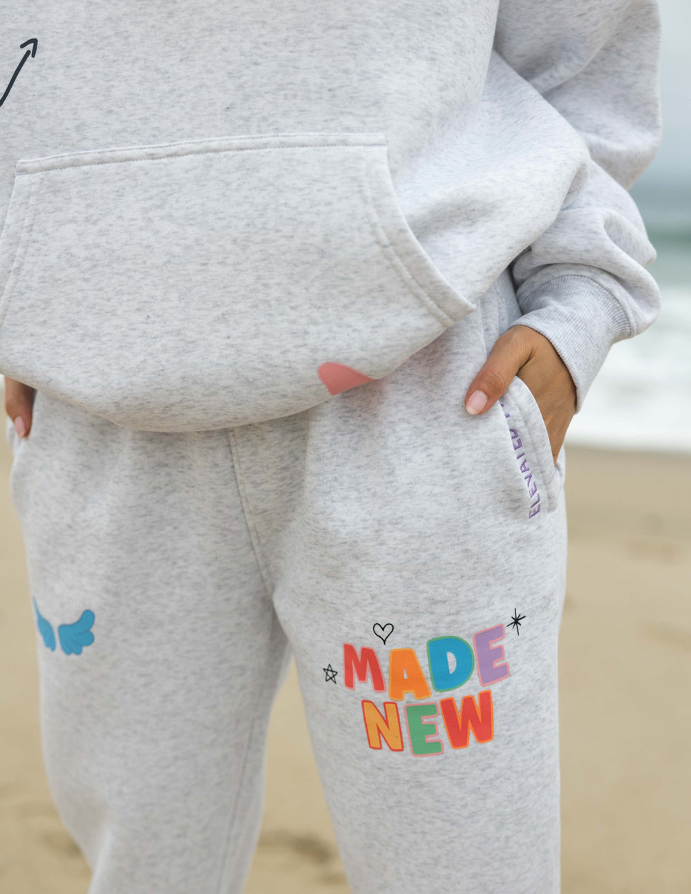 Heather gray sweatpants with "Made New" graphic on the front leg and small butterfly icons
