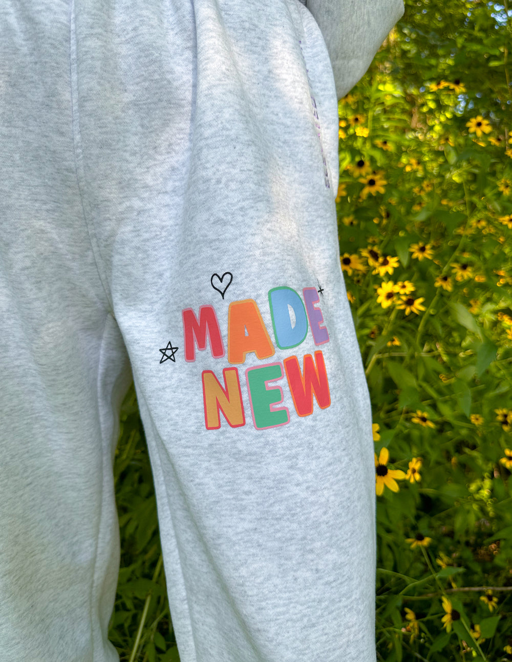 Heather gray sweatpants with large "Made New" graphic and small heart and star icons