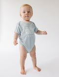 Light gray baby short-sleeve onesie with 'WORSHIP' front print