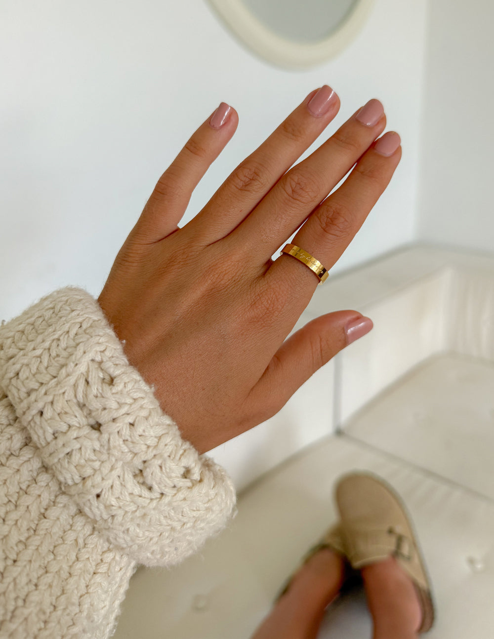 Gold-tone engraved band ring on finger, close-up