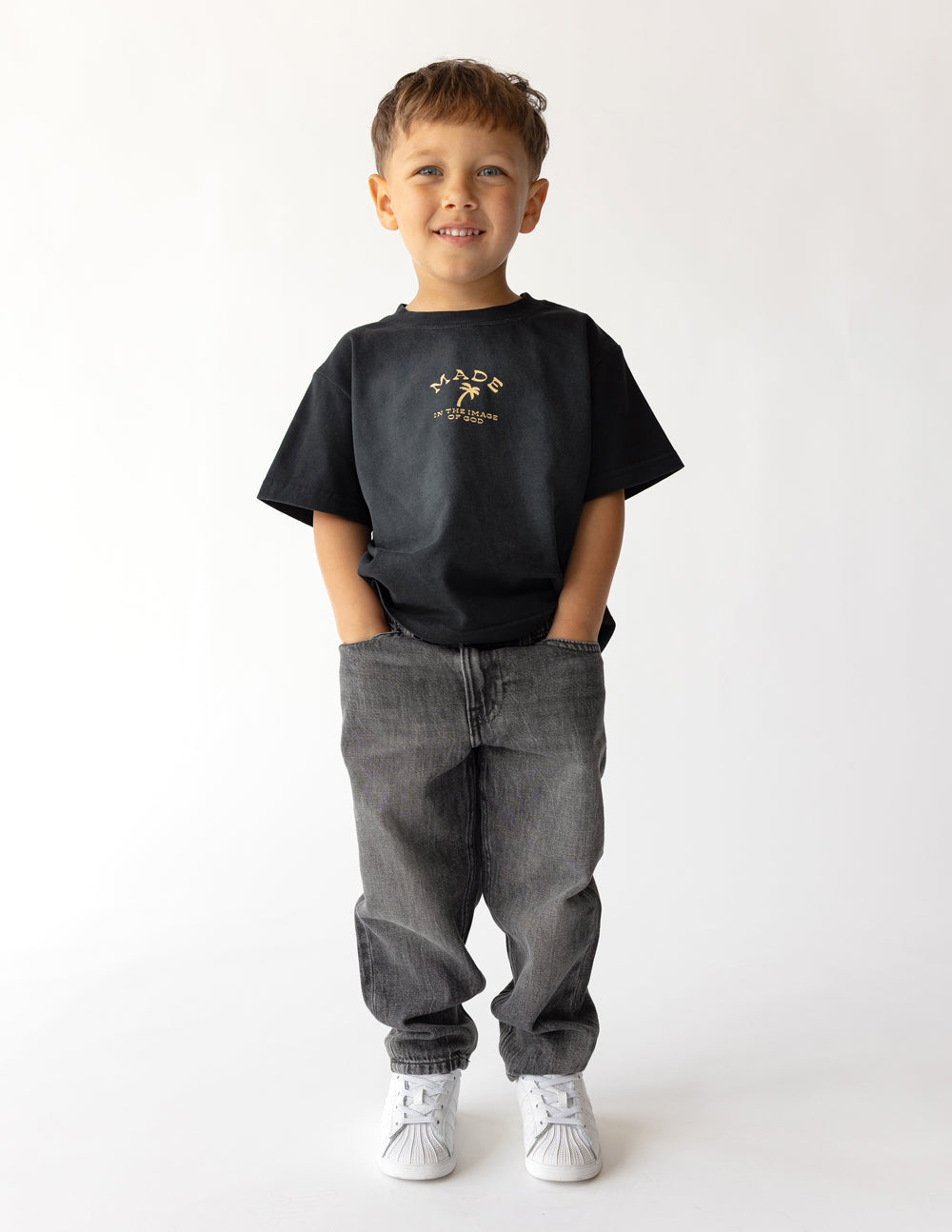 Kids black graphic tee with small gold scripture logo on chest